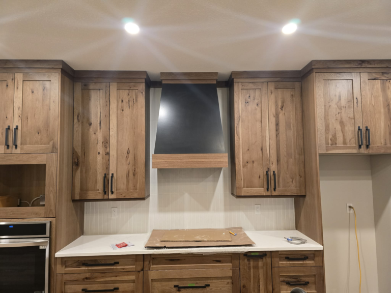 Wood kitchen cabinetry and hood surround during finishing work