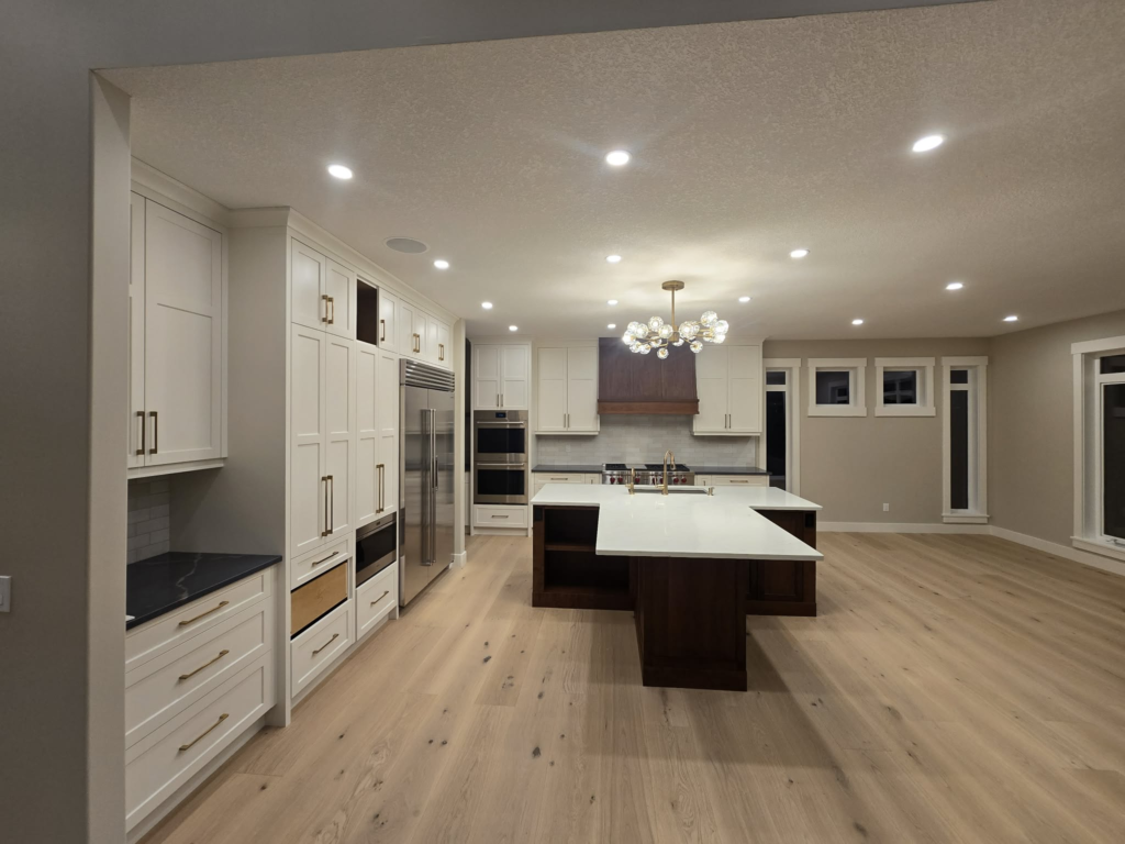 White kitchen cabinetry with a dark wood island and brass hardware
