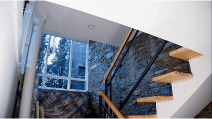 Bright white staircase and vaulted interior beside a natural stone feature wall.
