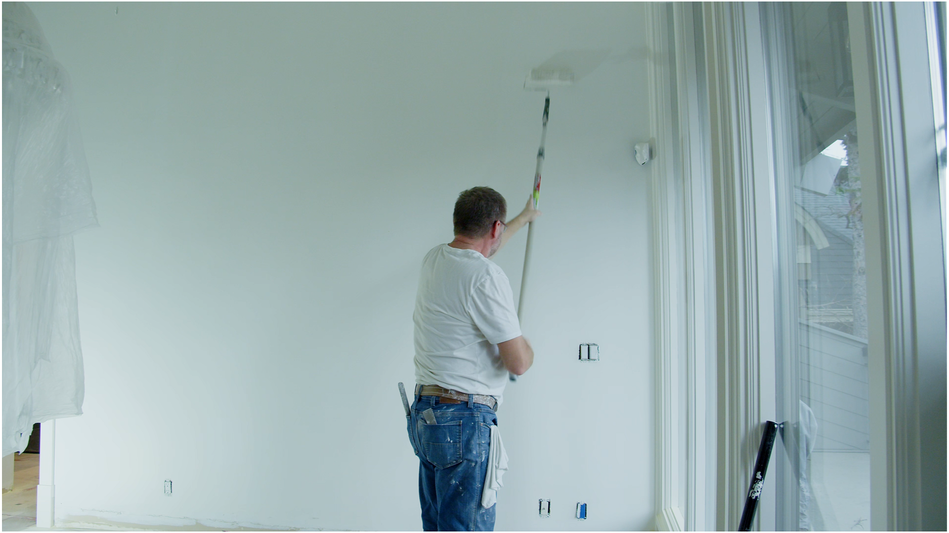 Admirari Solutions painter applying white paint to a high interior wall.