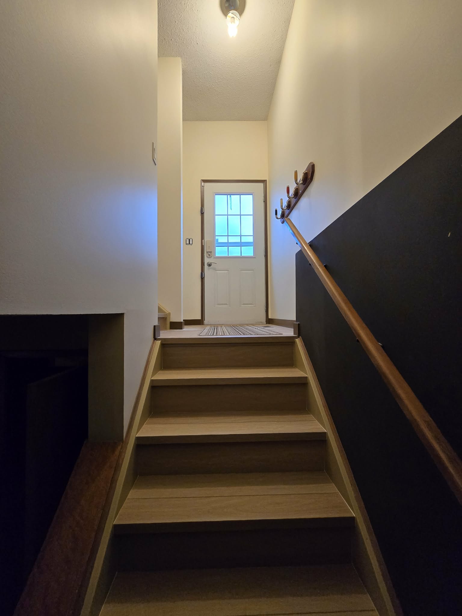 Updated stair flight with light flooring, painted walls, dark lower wall and wood handrail