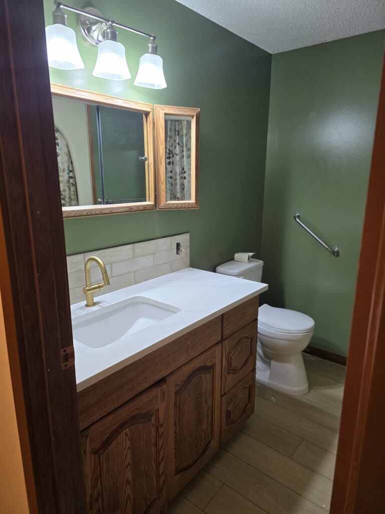 Bathroom vanity with light countertop, integrated sink, backsplash and existing wood cabinetry