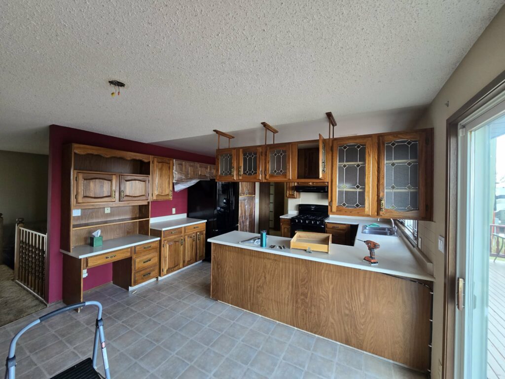 Wide kitchen view during early renovation work with original patterned flooring and protected work areas