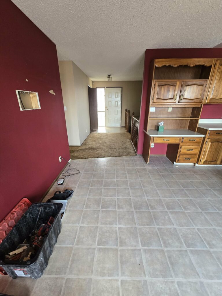 Kitchen and entry transition during early work showing patterned flooring meeting carpet
