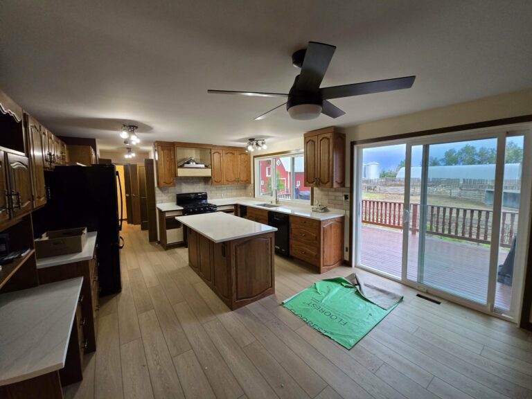 Wide late-stage kitchen view with light flooring, white countertops and retained wood cabinetry