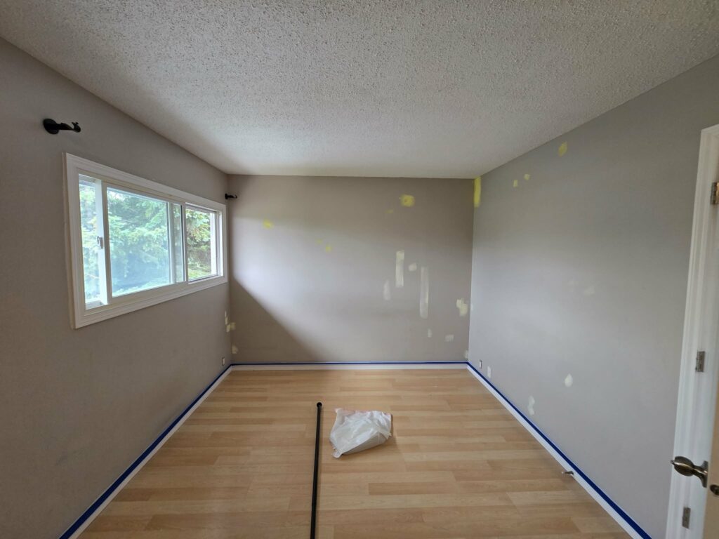 Bedroom walls repaired and baseboards masked before painting