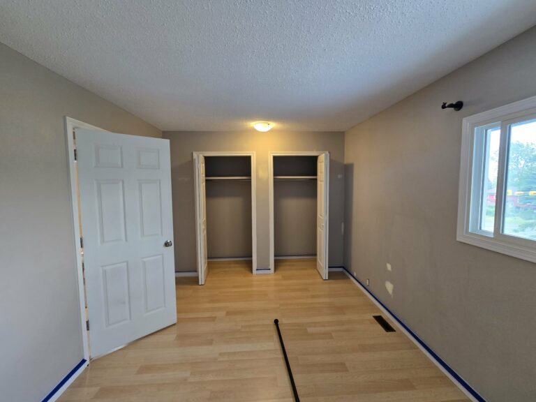Reverse bedroom view with repaired wall areas and masking visible