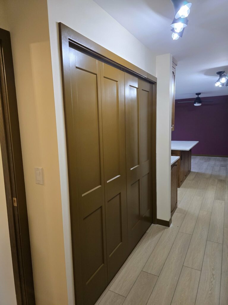 Closer hallway view highlighting dark-finished doors beside light flooring
