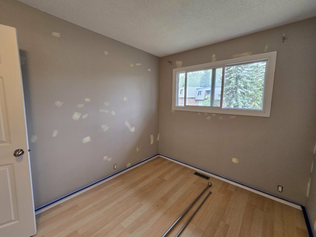 Wide bedroom view showing repaired wall areas and protected edges