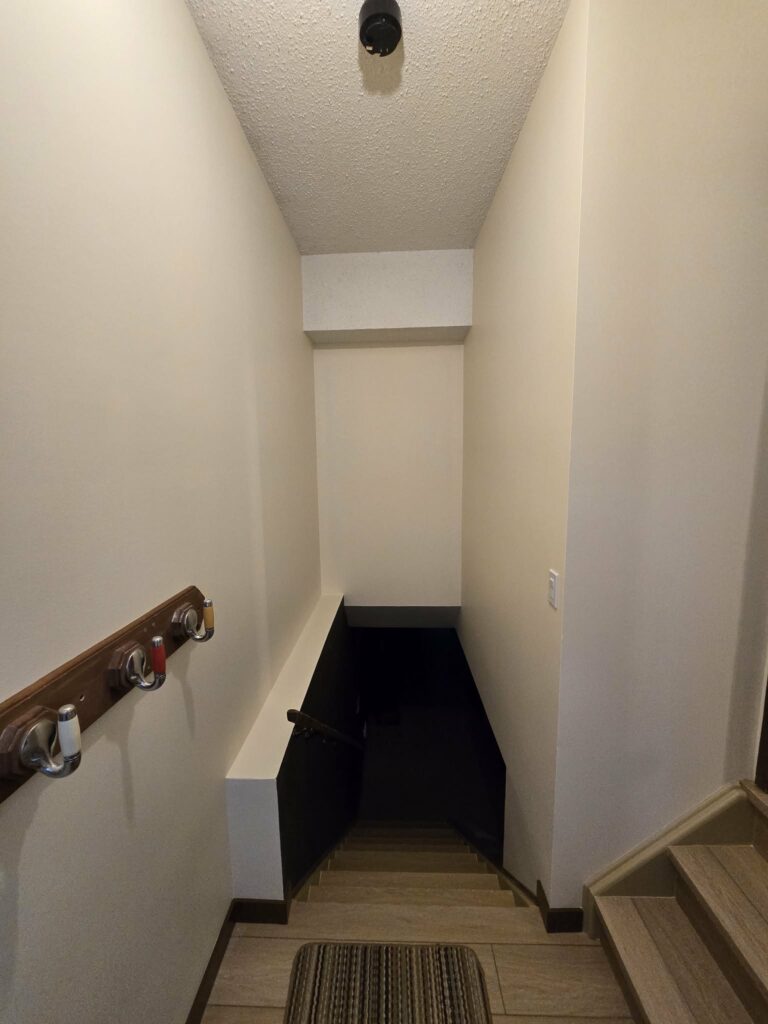 Painted stairwell viewed from above with contrasting dark lower wall and light stair finishes