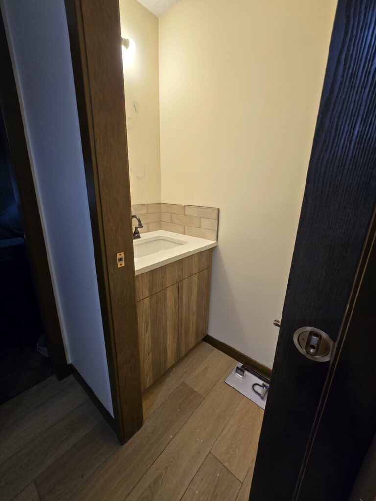 Powder-room vanity with light countertop, sink, faucet, backsplash and installation details visible
