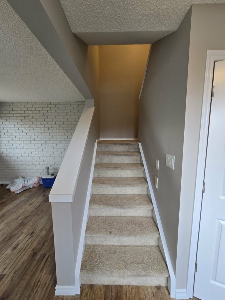 Stairwell during late-stage finishing with refreshed walls, trim and work supplies still present